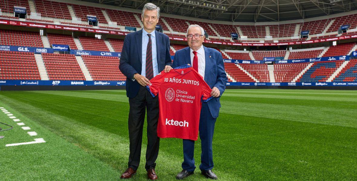 Foto de Luis Sabalza, presidente de Osasuna, y Joseba Campos, director general de la CUN, con la camiseta conmemorativa de la renovación del convenio entre la CUN y Osasuna en el césped del estadio El Sadar