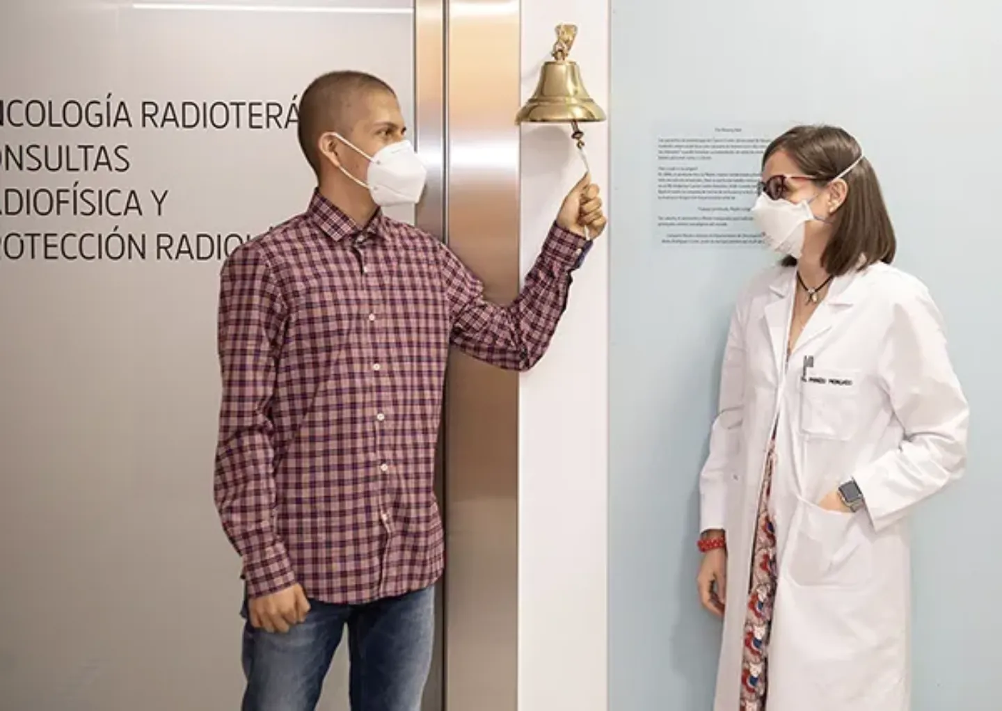 Paciente y Dra. Panizo. Campana Valientes. Historias de la Clínica Imagen del paciente junto a la Dra. Panizo tocando la Campana de los Valientes de su tratamiento con protones. Historias de la Clínica
