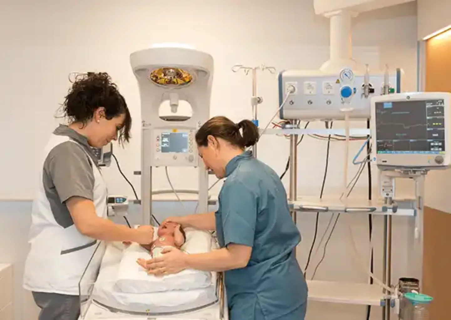 Estreno maternidad. Matronas con recién nacido Imagen de dos matronas de la Clínica Universidad de Navarra valorando a un bebé recién nacido en la UTPR de la Clínica Universidad de Navarra.