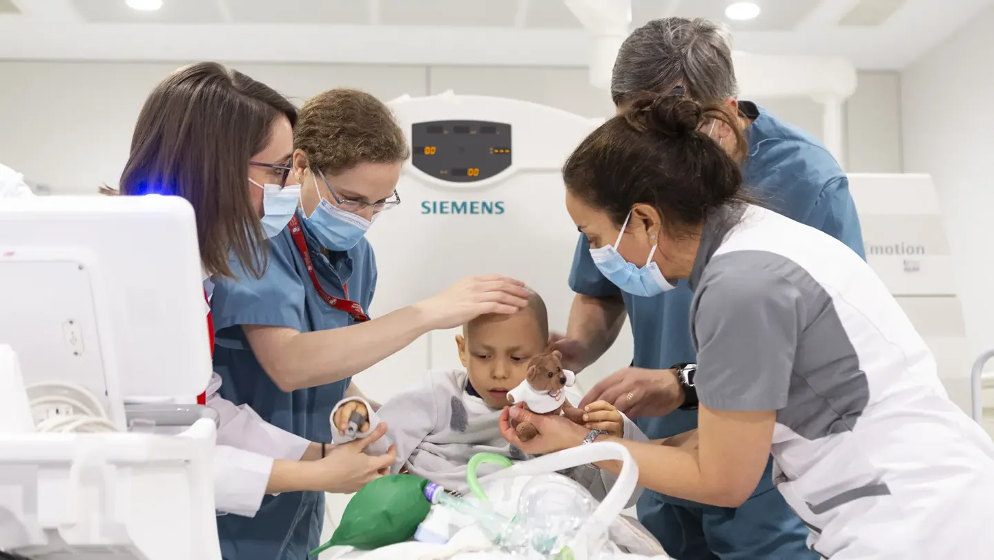 Equipo protonterapia con paciente. Clínica Universidad de Navarra Médicos y enfermeras junto a un paciente pediátrico preparándose para el tratamiento de protonterapia. Clínica Universidad de Navarra