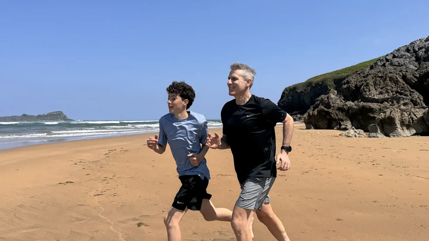 Imagen de Javier García, paciente de fibrilación auricular, corriendo por una playa con su hijo.