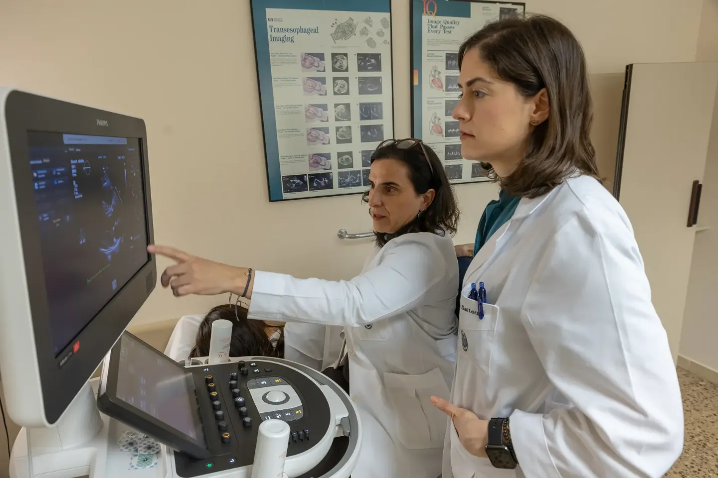 Imagen de una sala de ecocardiograma doppler con dos doctoras y una paciente tumbada en la camilla.