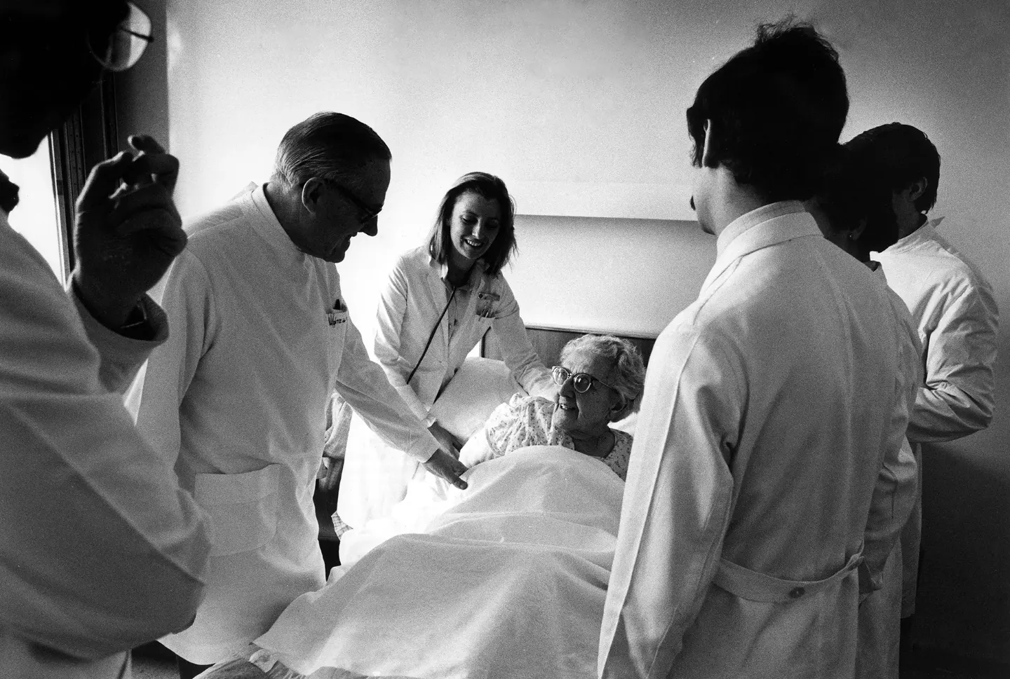 Imagen en blanco y negro de D. Eduardo Ortiz de Landázuri, junto a otros médicos, visitando a una paciente.