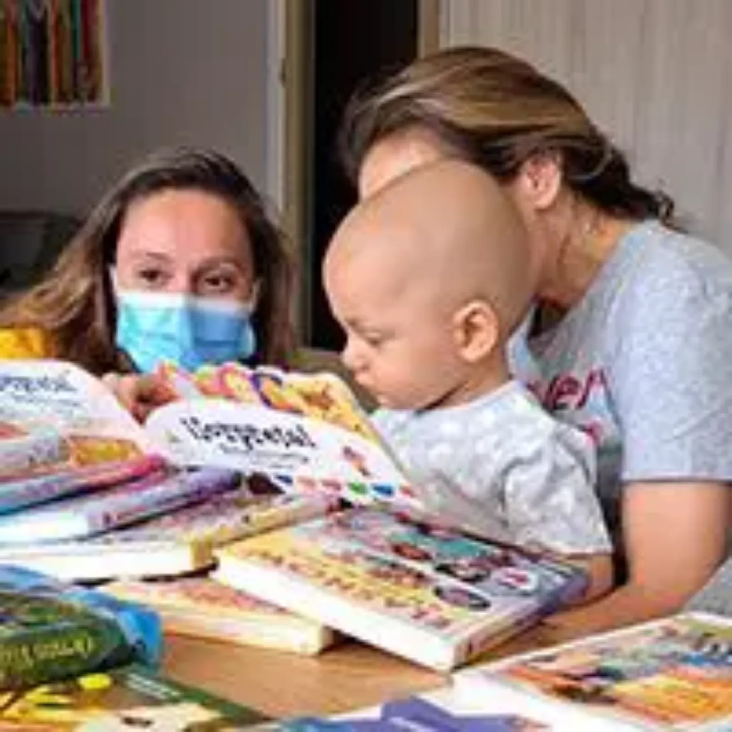 Imagen de un paciente pediátrico con dos mujeres leyendo cuentos infantiles. Clínica Universidad de Navarra