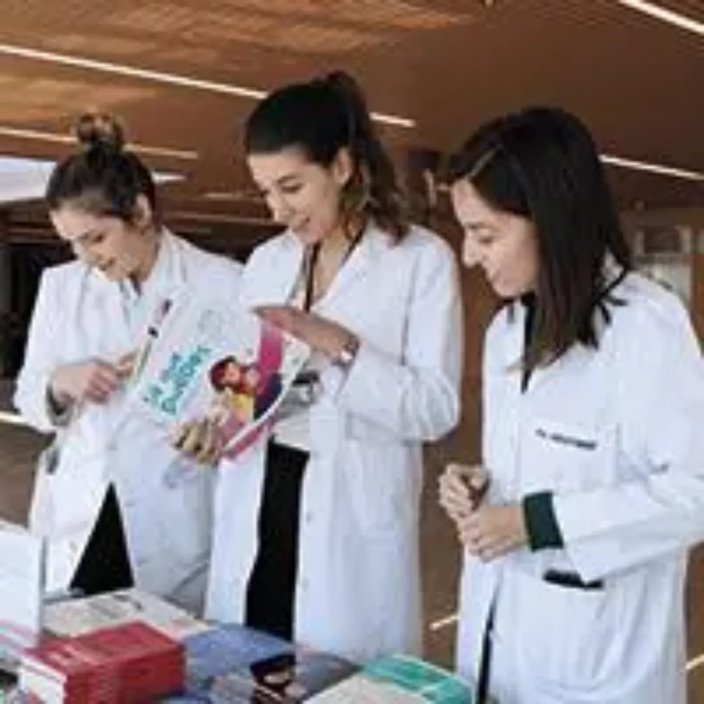 Tres doctoras mirando un stand con libros. Clínica Universidad de Navarra