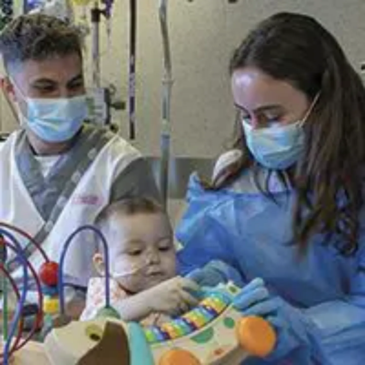 Un enfermero y una pedagoga jugando con un niño pequeño en la habitación de la UCI Pediátrica. Clínica Universidad de Navarra