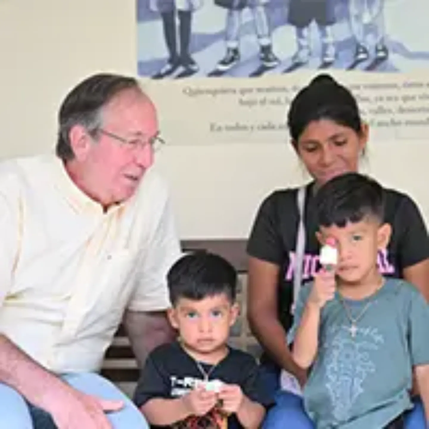 Imagen del Dr. Felipe Calvo sentado en un banco con una familia panameña. 