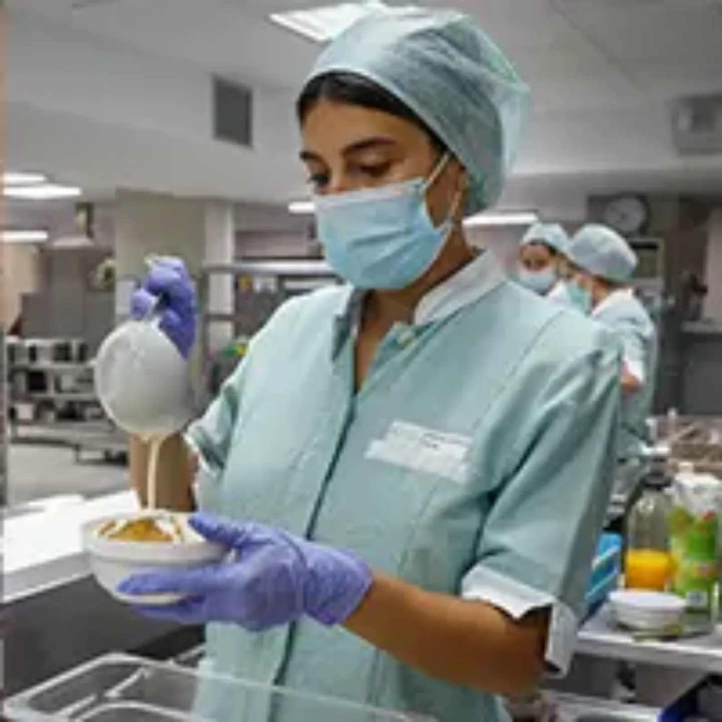 Imagen de una mujer preparando el postre para la comida de un paciente en la cocinas de la Clínica Universidad de Navarra.
