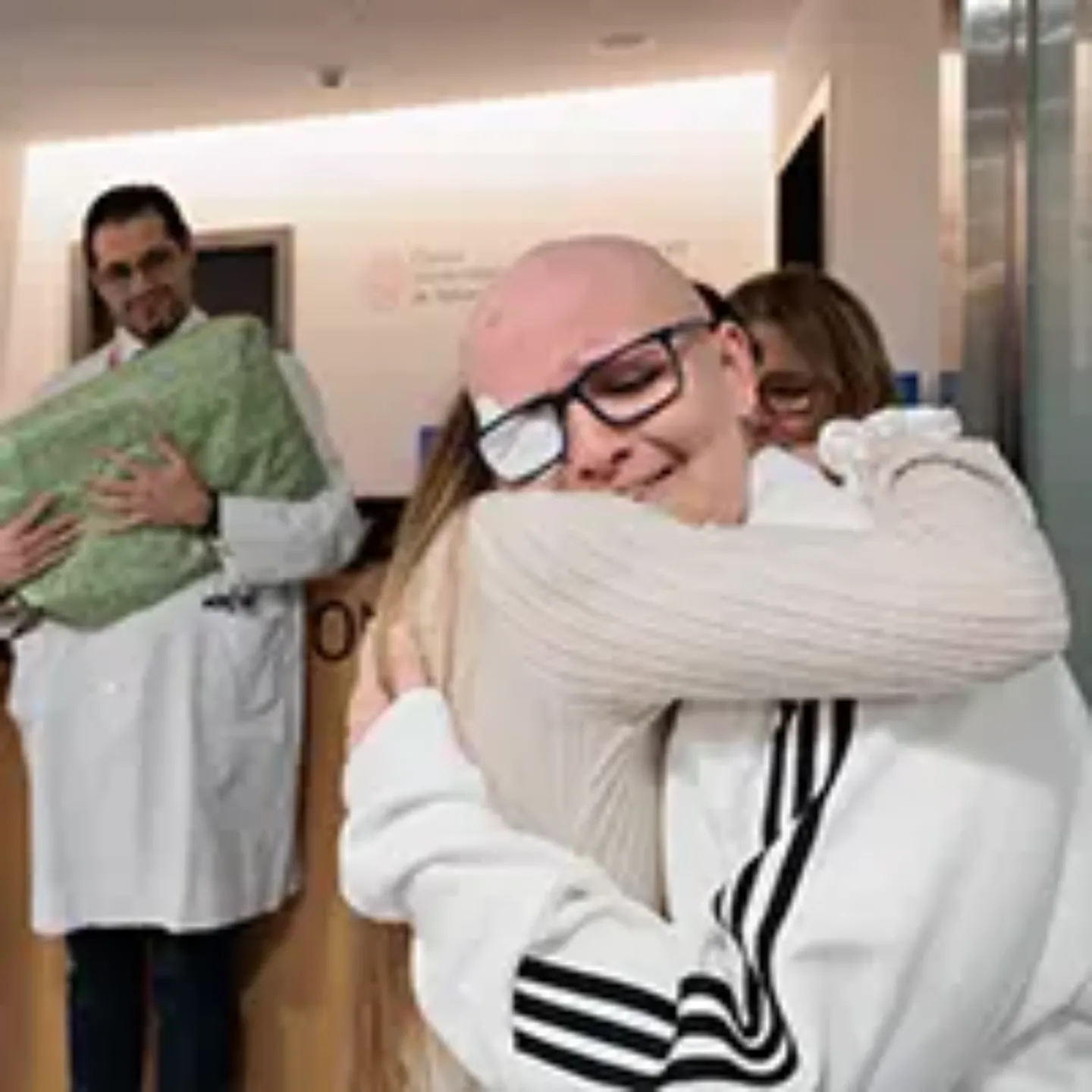 Un paciente adolescente de protonterapia abrazado a una auxiliar.