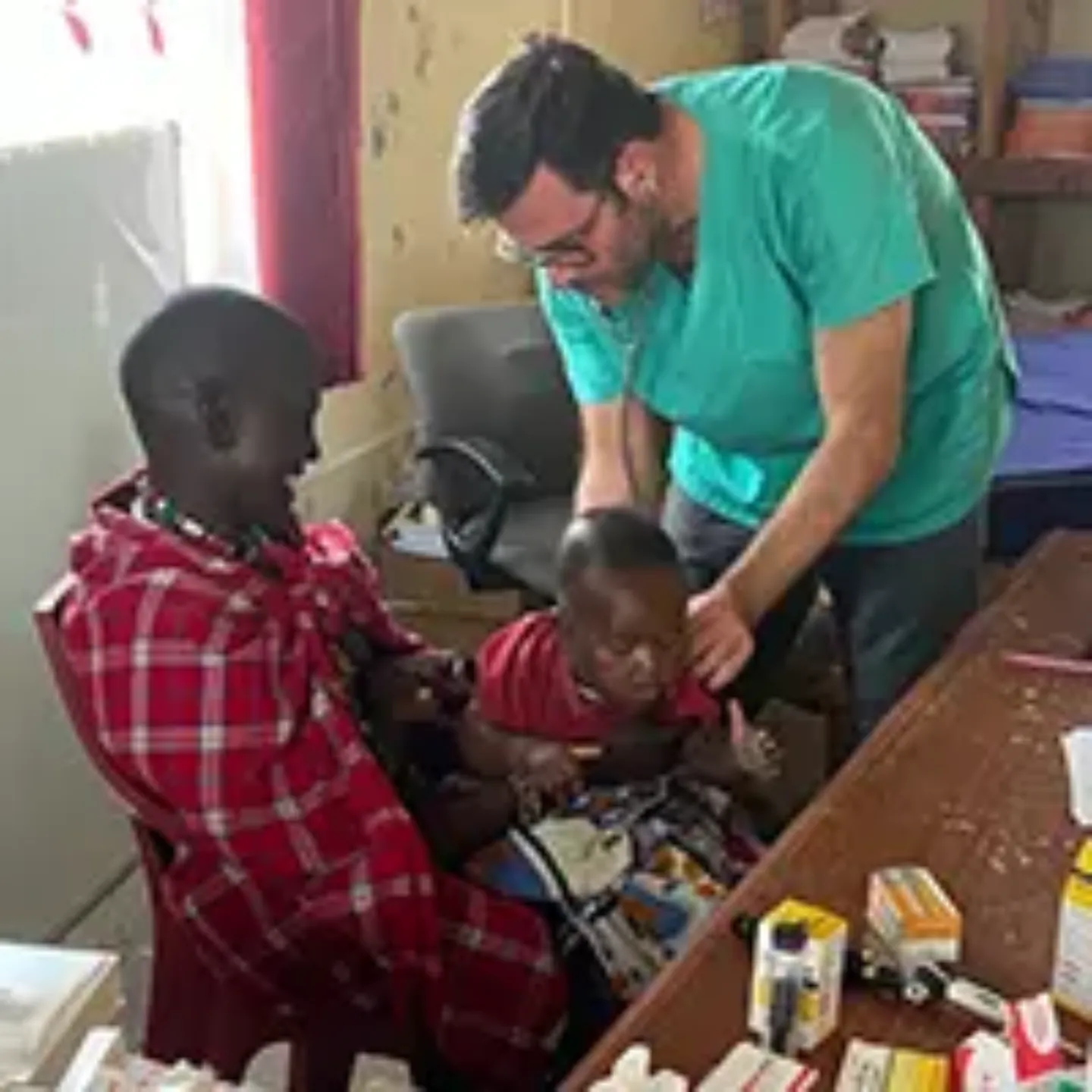Imagen de un médico de la Clínica Universidad de Navarra en África atendiendo a dos niños.