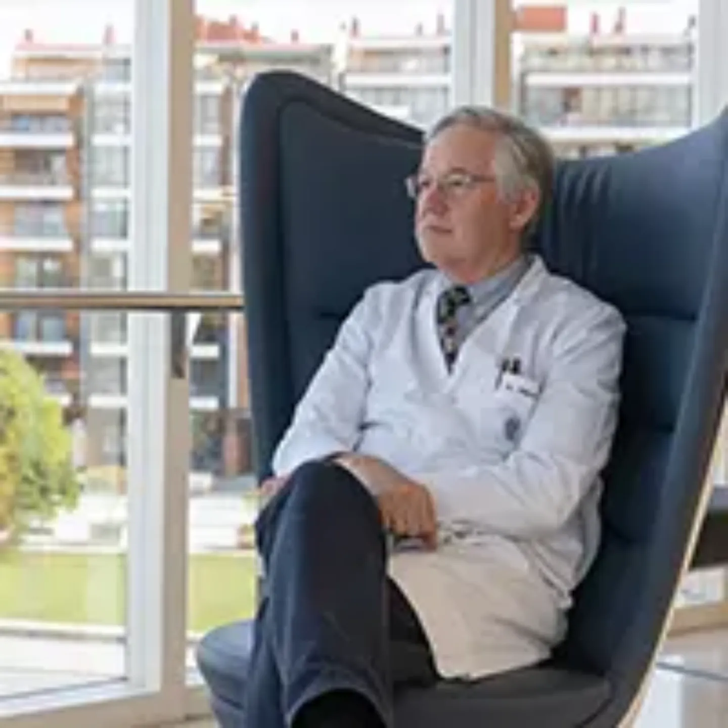Imagen de un médico cardiocirujano de la Clínica Universidad de Navarra sentado en una butaca mirando por una cristalera del hospital.