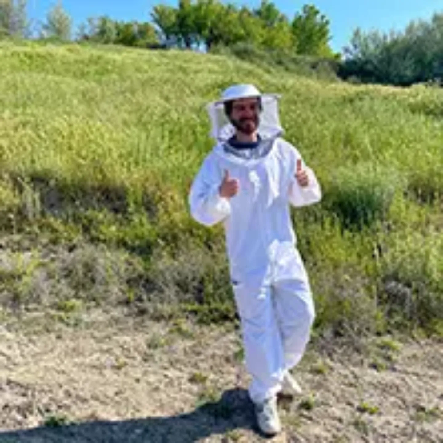 Imagen de un chico vestido de apicultor en el campo. 