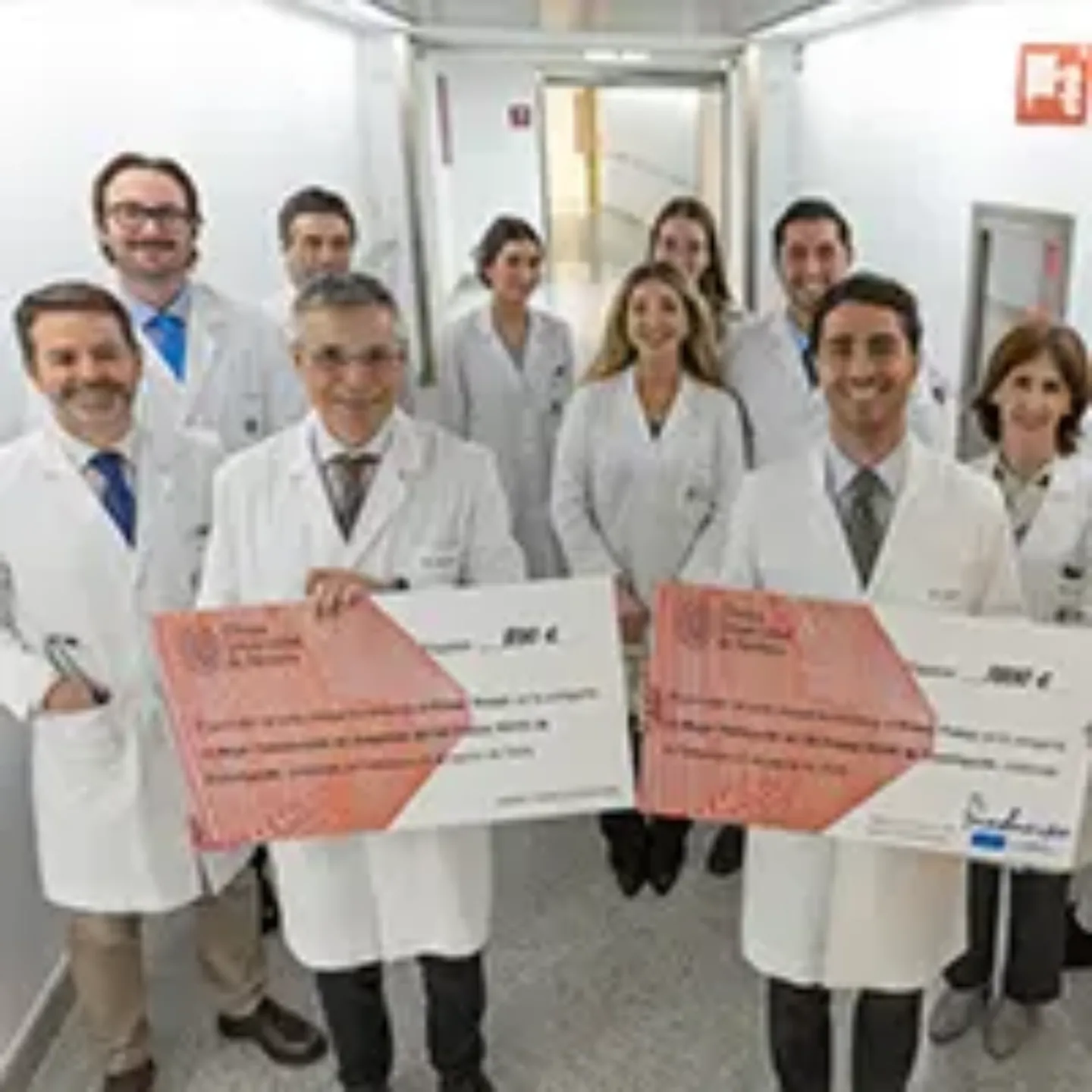 Imagen de varios médicos y residentes de la Clínica Universidad de Navarra con dos cheques grandes de los ganadores.