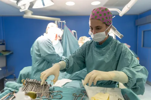 Imagen de un quirófano de la Clínica Universidad de Navarra con una cirujana en primer plano revisando el instrumental de una mesa. 