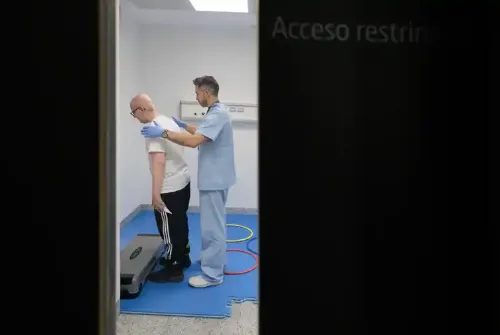 Imagen de Enric, paciente adolescente de la Unidad de Protonterapia de la Clínica Universidad de Navarra, con el fisioterapeuta haciendo ejercicios en la sala de rehabilitación.