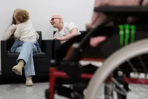 Imagen de Enric, paciente adolescente de la Unidad de Protonterapia de la Clínica Universidad de Navarra, sentado en la sala de espera del hospital junto con su familia.