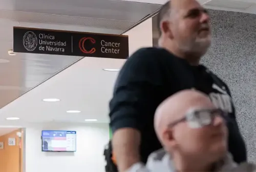 Imagen de Enric y su padre en un pasillo de la Clínica Universidad de Navarra en Madrid donde se ve un cartel del CCUN colgado del techo.