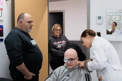 Imagen de Enric, paciente adolescente de la Unidad de Protonterapia de la Clínica Universidad de Navarra, con sus padres en una consulta mientras una doctora le explora.