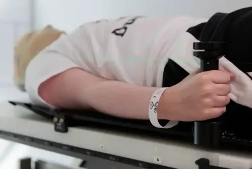 Imagen de Enric, paciente adolescente de la Unidad de Protonterapia de la Clínica Universidad de Navarra, tumbado en la camilla del gantry con la máscara de radioterapia colocada.