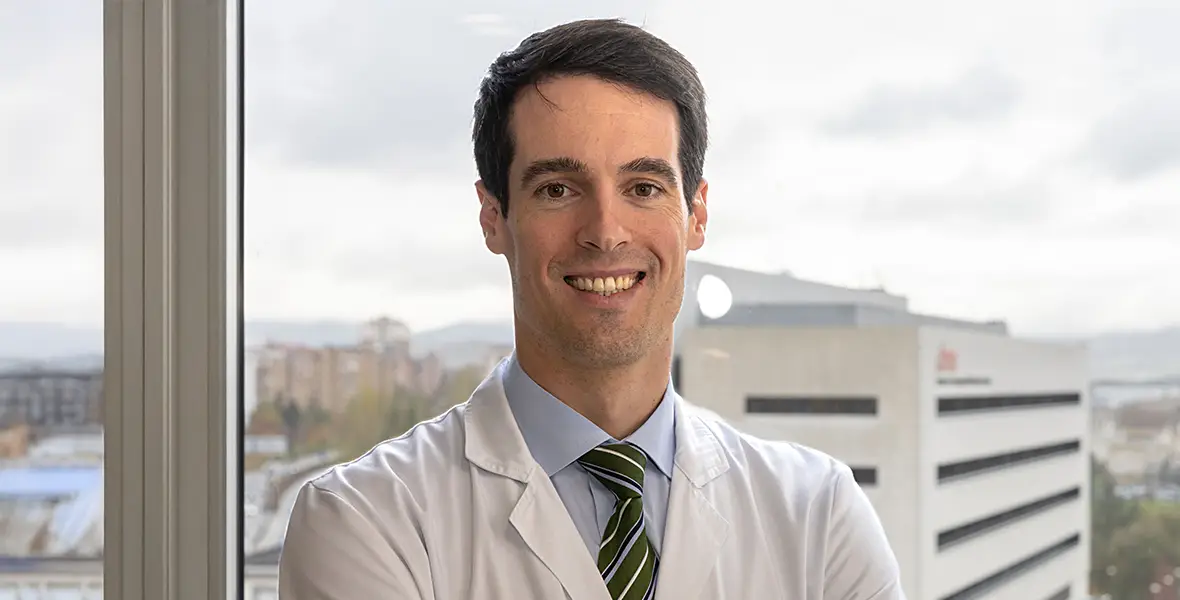 Foto del Dr. Iñaki Eguren, oncólogo de la Clínica investigador del Grupo de Onco-Inmunología Aplicada y Traslacional con el Cima Universidad de Navarra de fondo. 