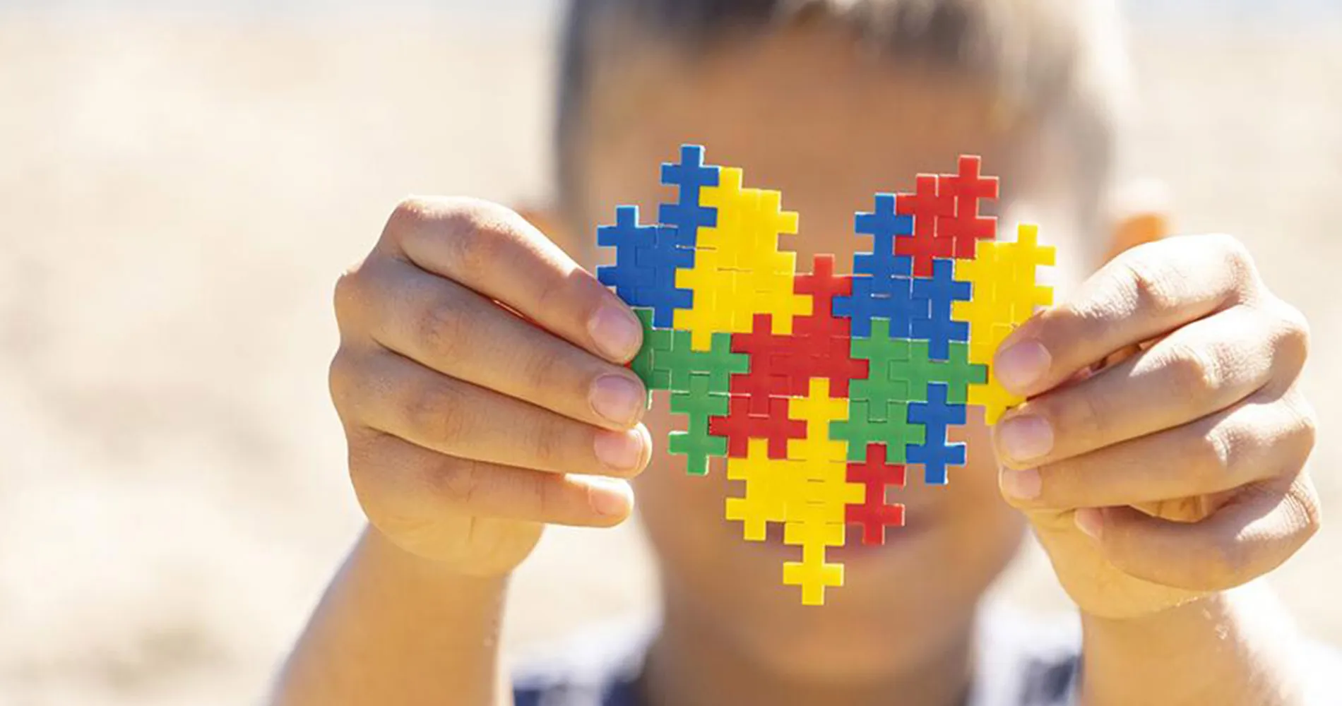 Niño con síndrome de Asperger. CUN Imagen un niño en la playa con un puzzle de colores