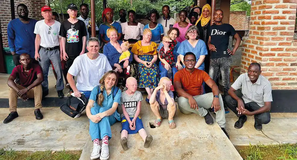Grupo participante del proyecto Dermalawi. Imagen de grupo de los médicos y pacientes en la entrada del hospital de Malawi inmerso en el proyecto Dermalawi para la atención de personas albinas en el que participan dermatólogos de la Clínica Universidad de Navarra.