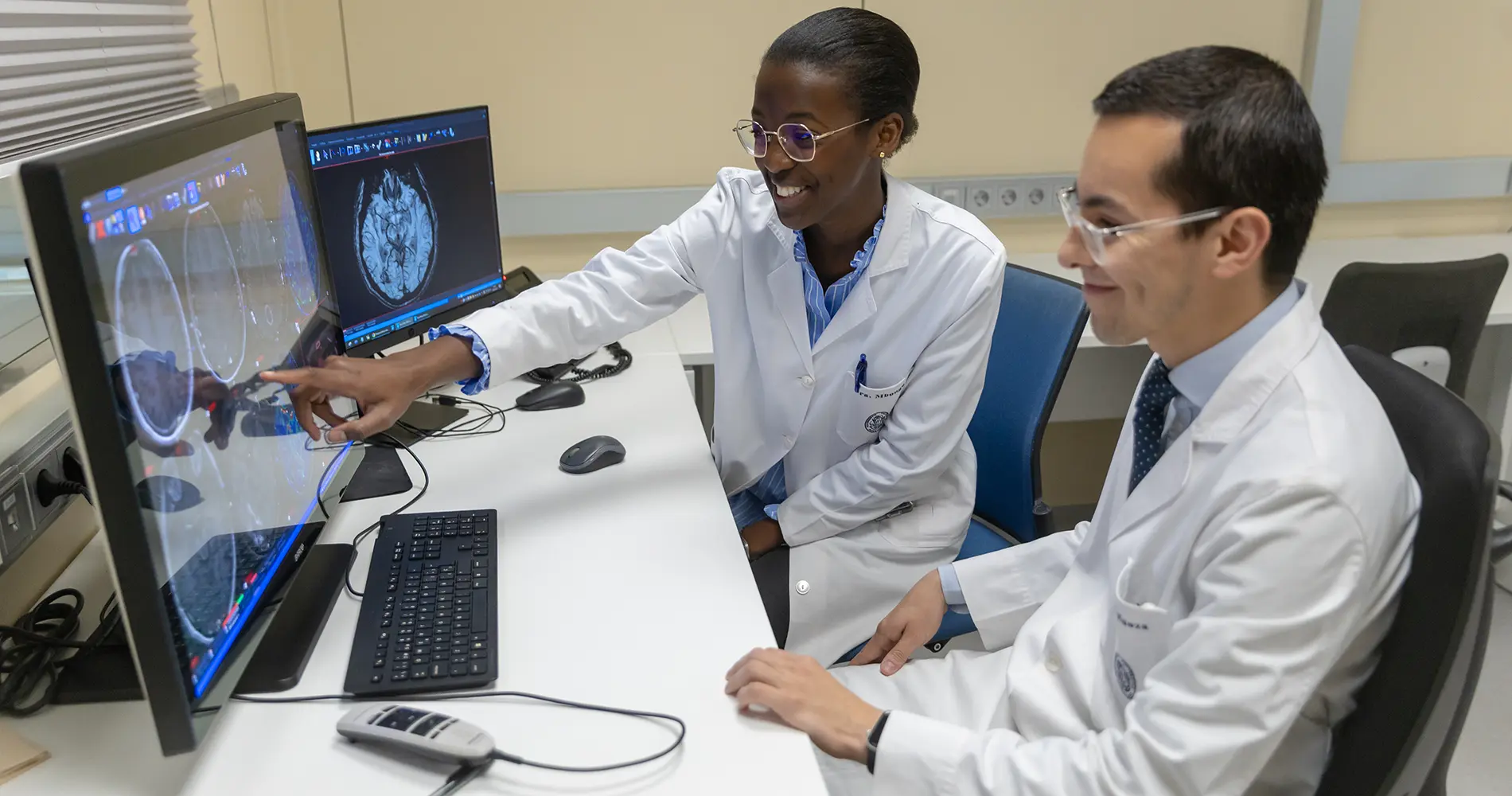 Residentes por el mundo. Carmen Mbongo - Christian Espinoza Los residentes Carmen Mbongo y Christian Espinoza en la sala de informes de Radiología revisando imágenes cerebrales en el ordenador.